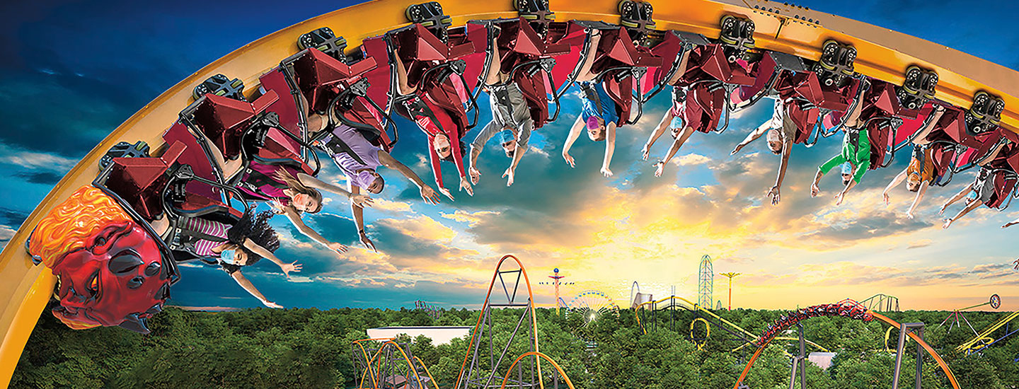 People hanging upside down on the track of a rollercoaster with their arms up